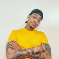 a man in a yellow t - shirt with tattoos on his arms