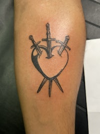 a tattoo of a heart with two swords on it